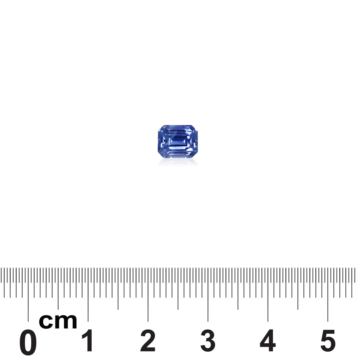 Un Saphir Bleu de 1,61 ct de Bonnot Paris repose sur un fond blanc avec une règle en dessous, indiquant que la pierre précieuse exquise de taille émeraude mesure moins de 1 cm de longueur.