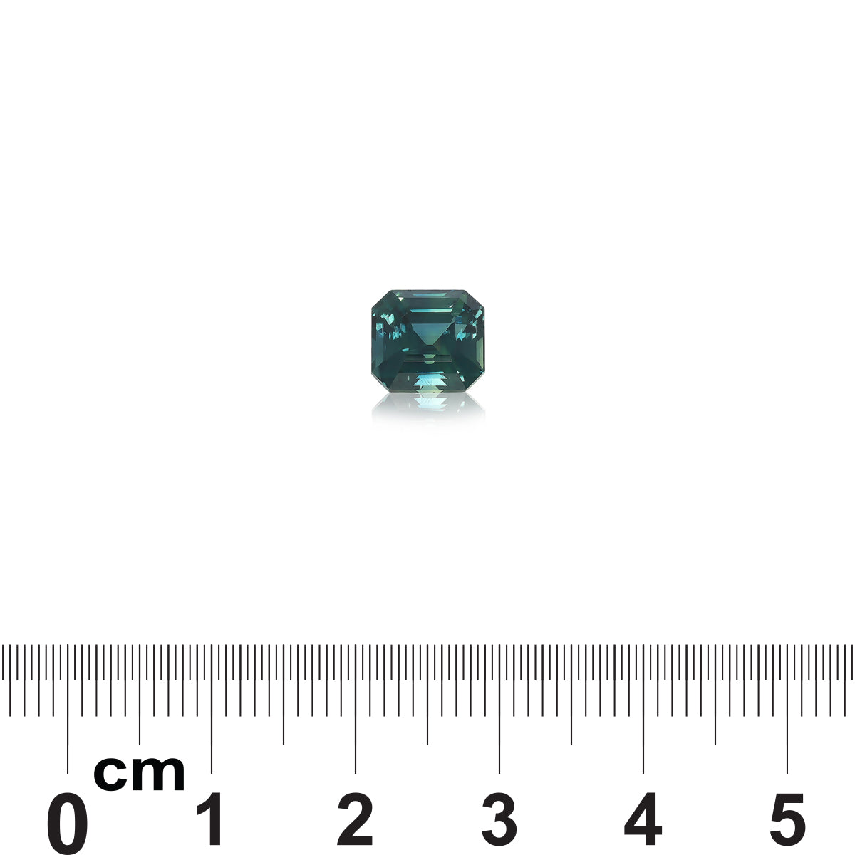 Un Saphir Teal de 3,03 ct de Bonnot Paris, une petite pierre précieuse verte facettée, est placé sur un fond blanc au-dessus d'une règle avec des mesures en centimètres, indiquant qu'il mesure environ 0,6 cm de large.
