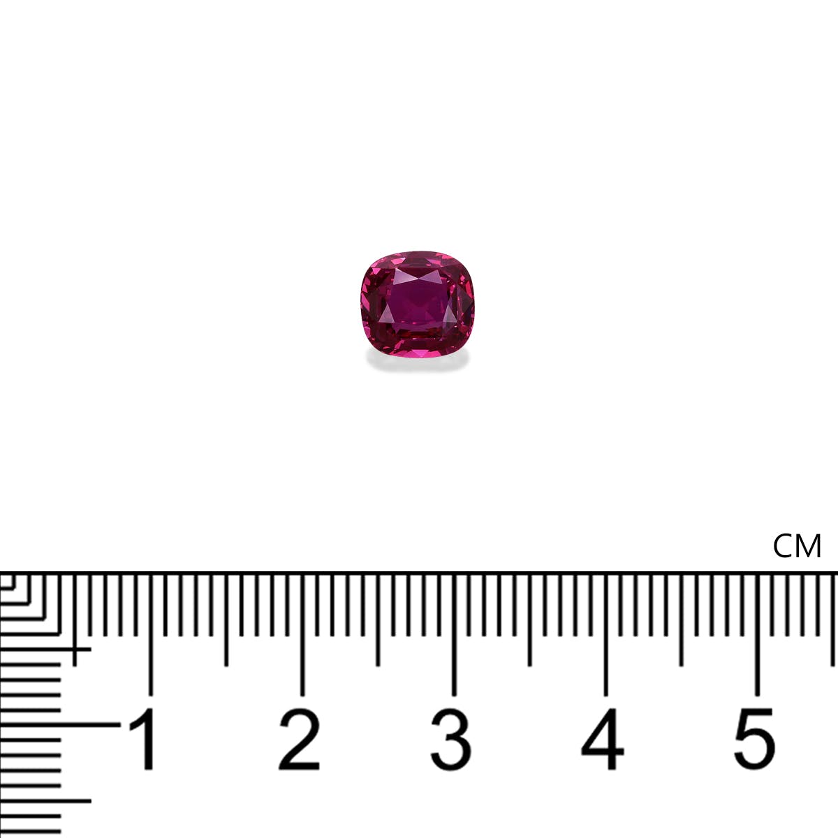 Le Saphir Rose · 2,55 ct de Bonnot Paris, une pierre précieuse rubis taille coussin rouge foncé, repose sur une surface blanche à côté d'une règle centimétrique, montrant sa surface polie et réfléchissante et sa taille inférieure à 1 cm.
