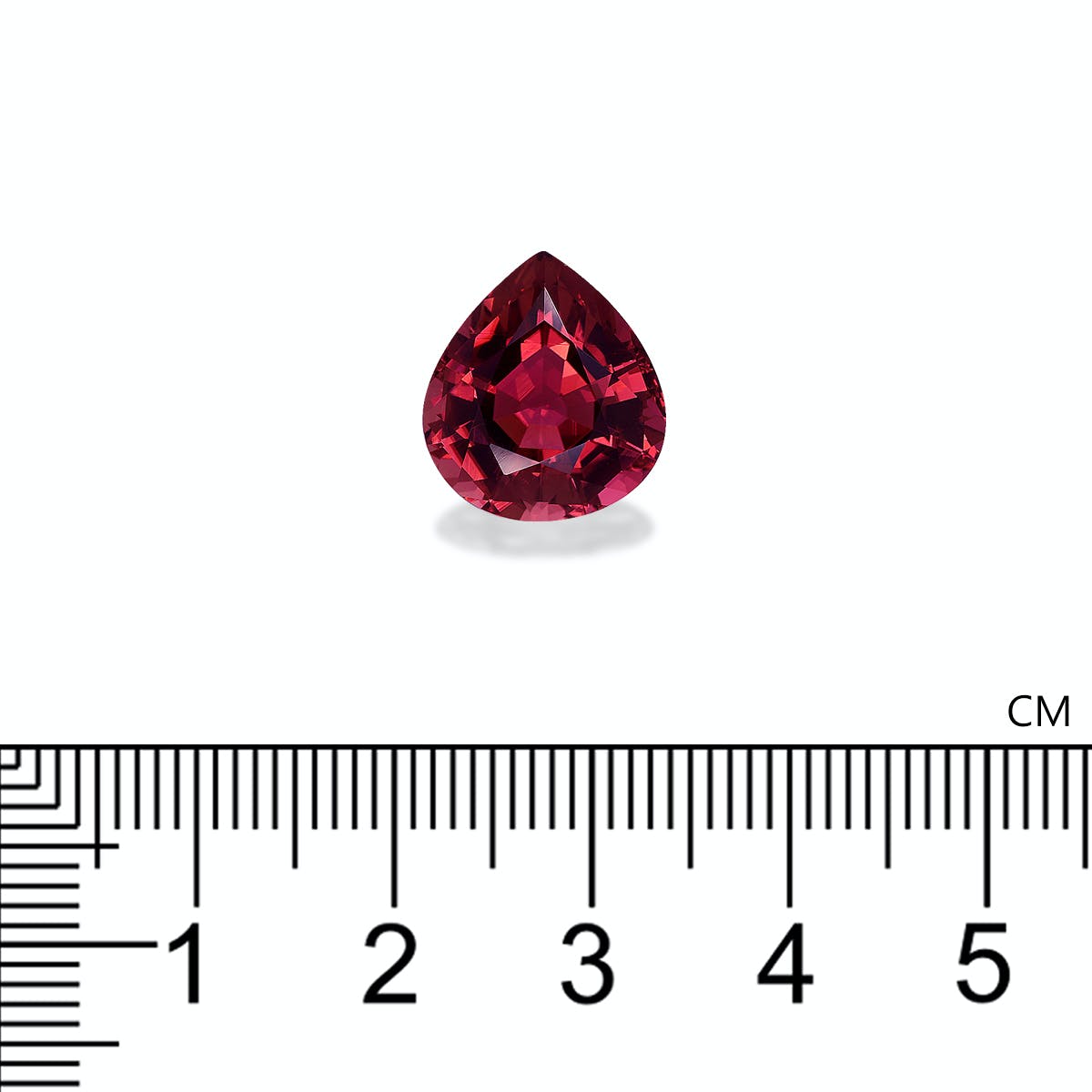 Placée au-dessus d'une règle graduée, la tourmaline rose Bonnot Paris reflète la lumière à travers ses facettes d'un rouge profond. Cette pierre de 7,26 carats, taillée en poire, mesure un peu plus d'1 cm de haut.