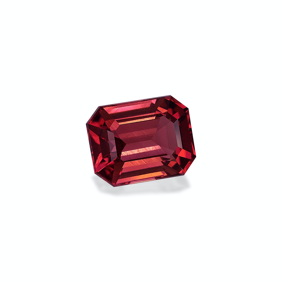 Une Tourmaline Rose, pierre précieuse de 6,25 ct de Bonnot Paris, présente une taille émeraude rouge avec une forme rectangulaire et des bords biseautés, projetant une ombre douce sur un fond blanc.