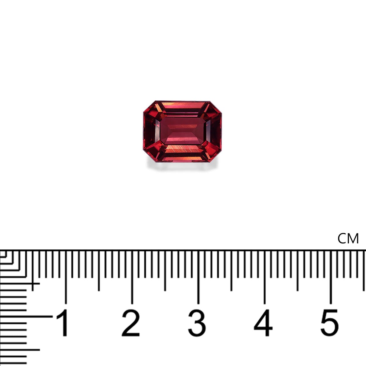 Une tourmaline rose de 6,25 carats de Bonnot Paris, petite pierre rectangulaire rouge taille émeraude, est placée au-dessus d'une règle métrique sur fond blanc. La règle, en centimètres, indique une longueur d'environ 0,8 cm.