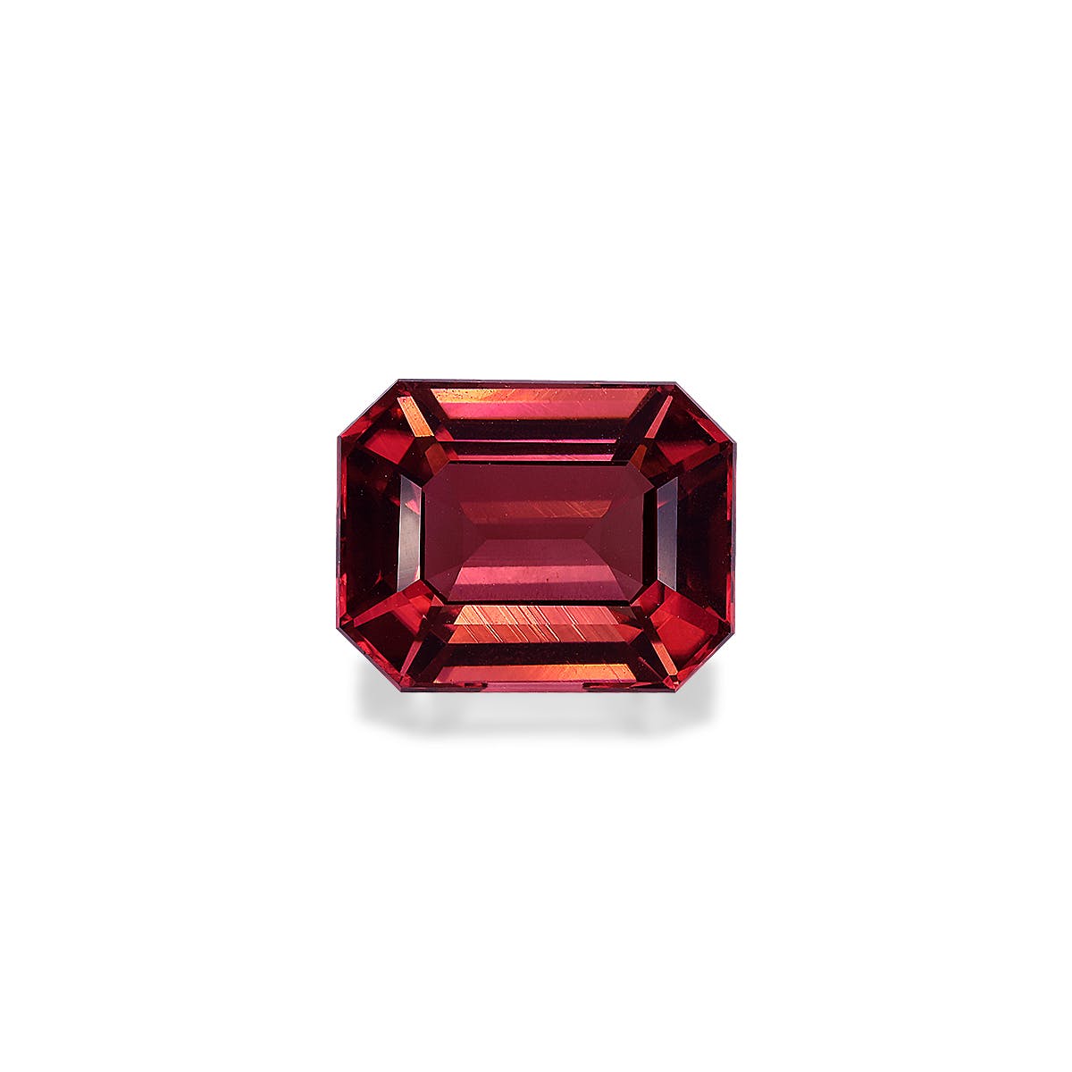 Une Tourmaline Rose taille émeraude de 6,25 carats de Bonnot Paris, aux teintes rouges vibrantes et aux multiples facettes reflétant la lumière pour des nuances et une brillance variées, sur un fond blanc uni.