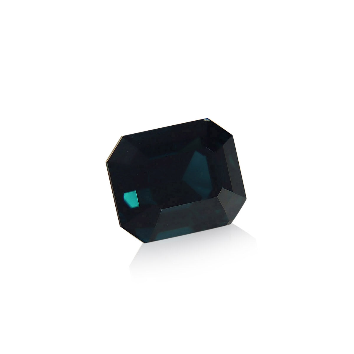 Le Saphir Teal de Bonnot Paris est une pierre précieuse taille émeraude foncée de 4,04 carats présentant une teinte bleu profond qui reflète magnifiquement la lumière sur un fond blanc.