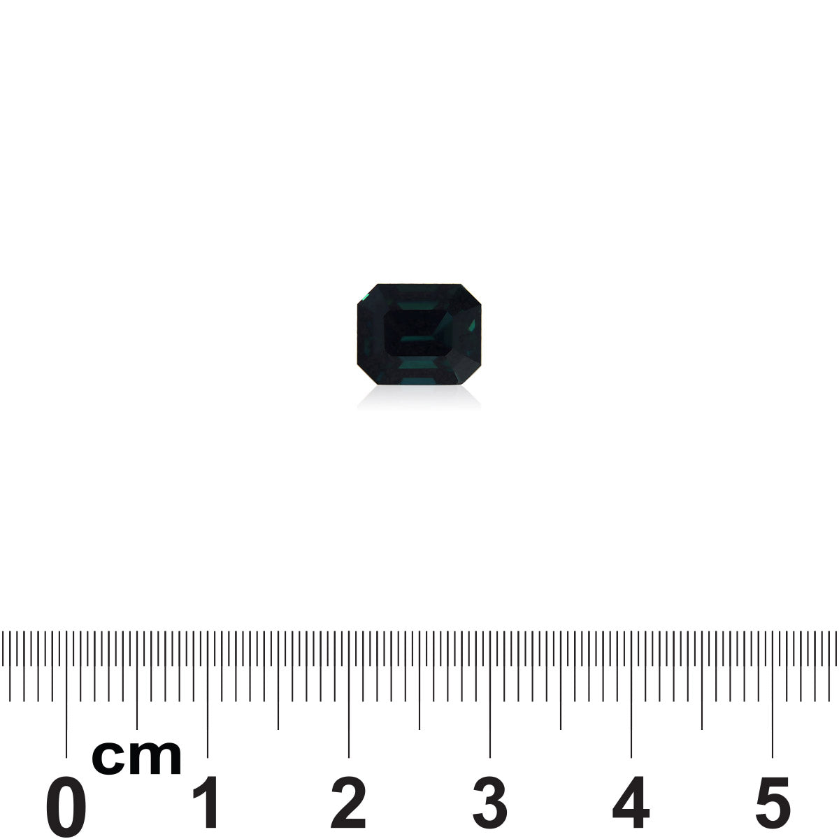 Un saphir bleu sarcelle de 4,04 ct de Bonnot Paris, une petite pierre rectangulaire vert foncé, est placé sur un fond blanc. En dessous, une règle graduée en centimètres indique sa taille : environ 0,6 cm.