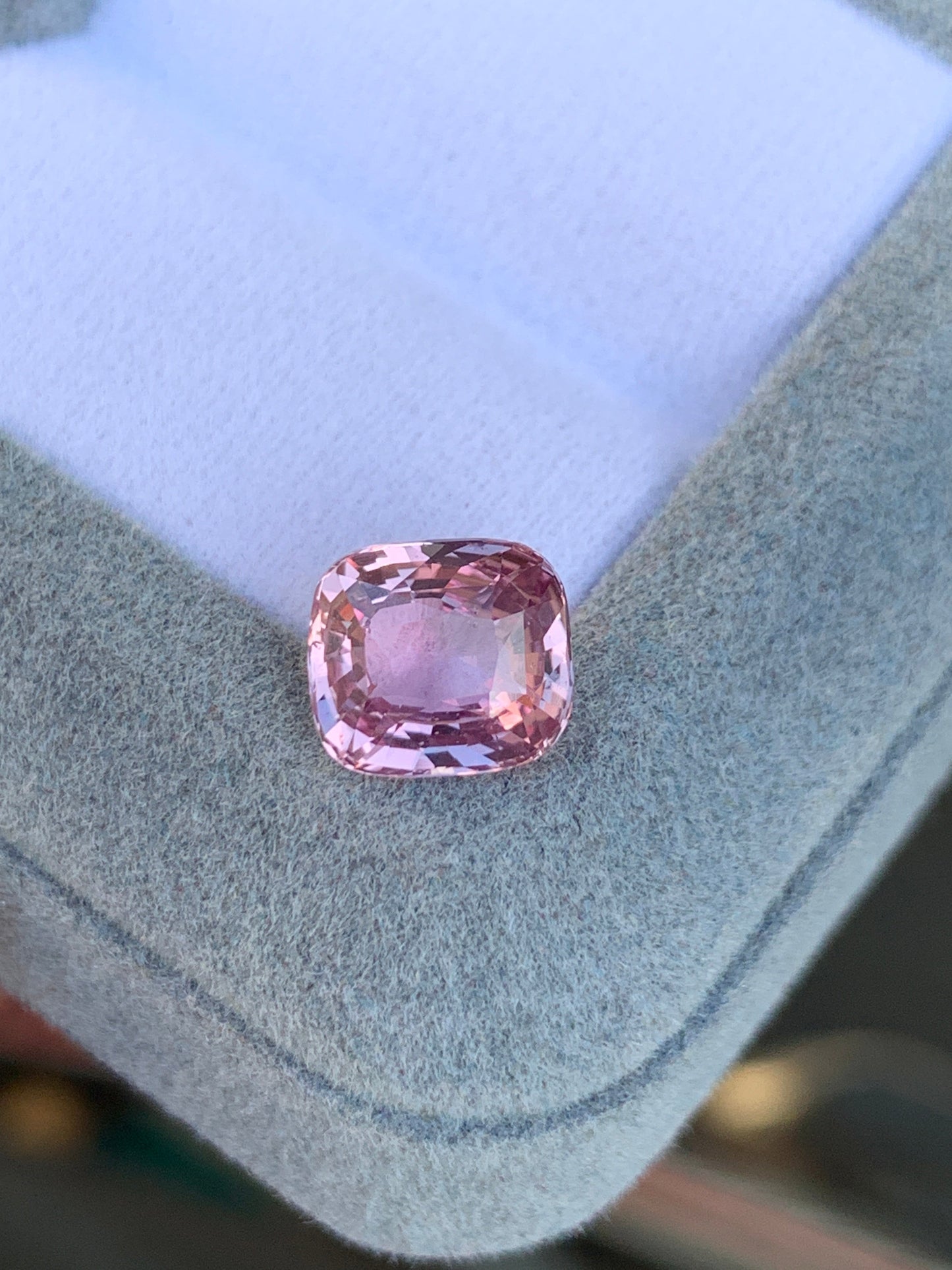 Le Saphir Rose • 3,05 carats de Bonnot Paris, une pierre rose taille coussin, est présenté sur un velours gris clair sur fond blanc. Ses facettes captent et reflètent la lumière, soulignant sa clarté et sa couleur vibrante.
