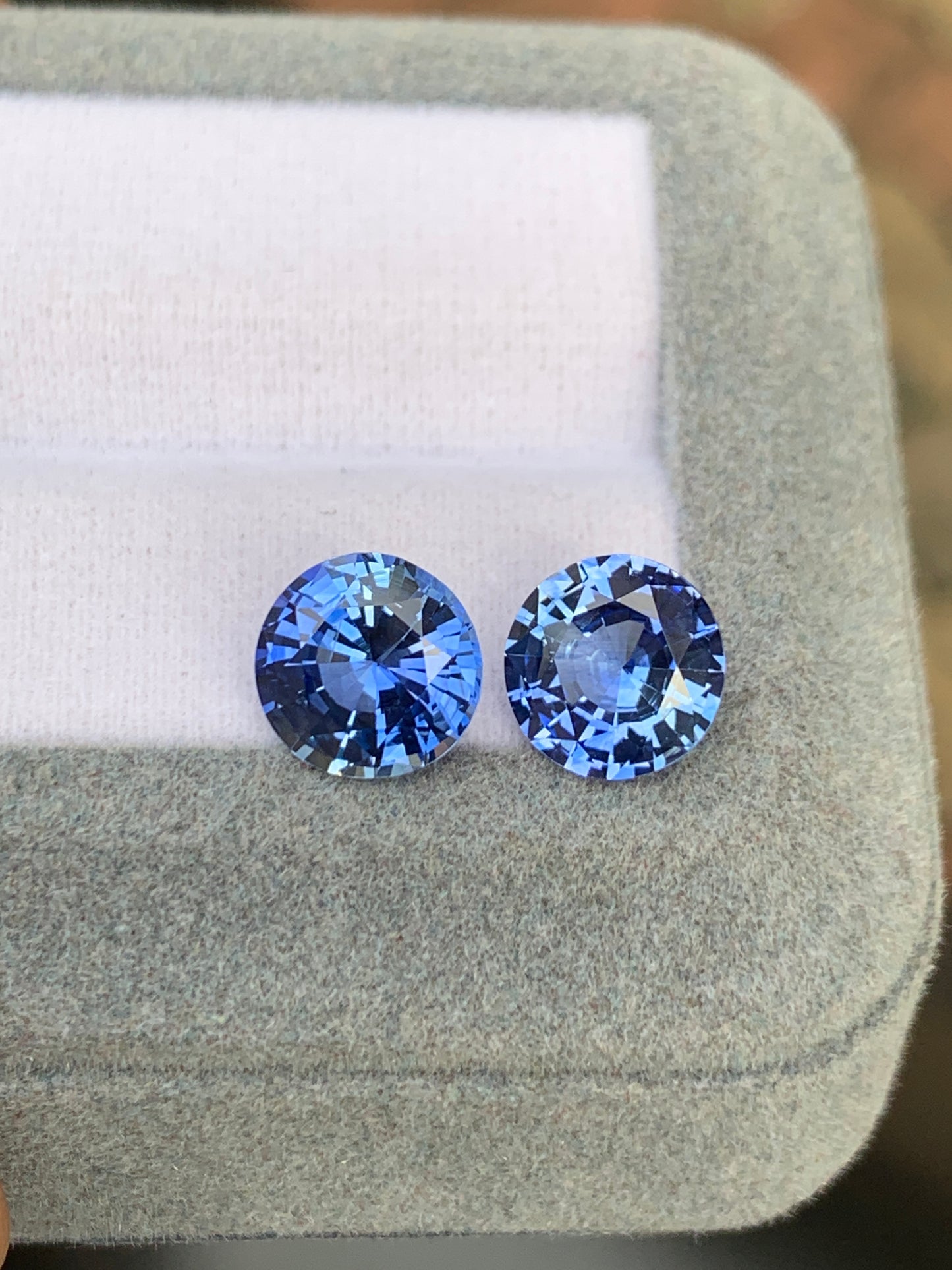 Dans un écrin gris matelassé, deux Saphir bleu de Bonnot Paris, totalisant 5,65 carats, captivent par leur teinte bleue éclatante. Taillées avec soin pour sublimer leur éclat et leur clarté, ces pierres précieuses reposent élégamment sur un fond de tissu blanc.