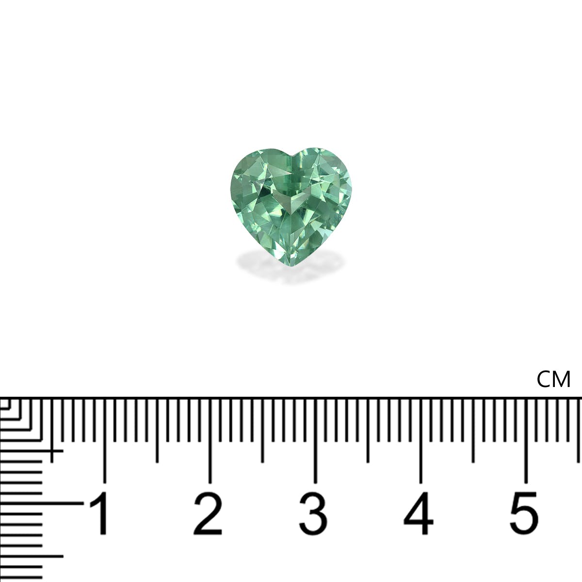 Une Tourmaline Verte en forme de cœur de 5,65 ct de Bonnot Paris repose sur une surface blanche, avec une règle noire en centimètres en dessous indiquant que la pierre précieuse mesure environ 1,5 cm de large.