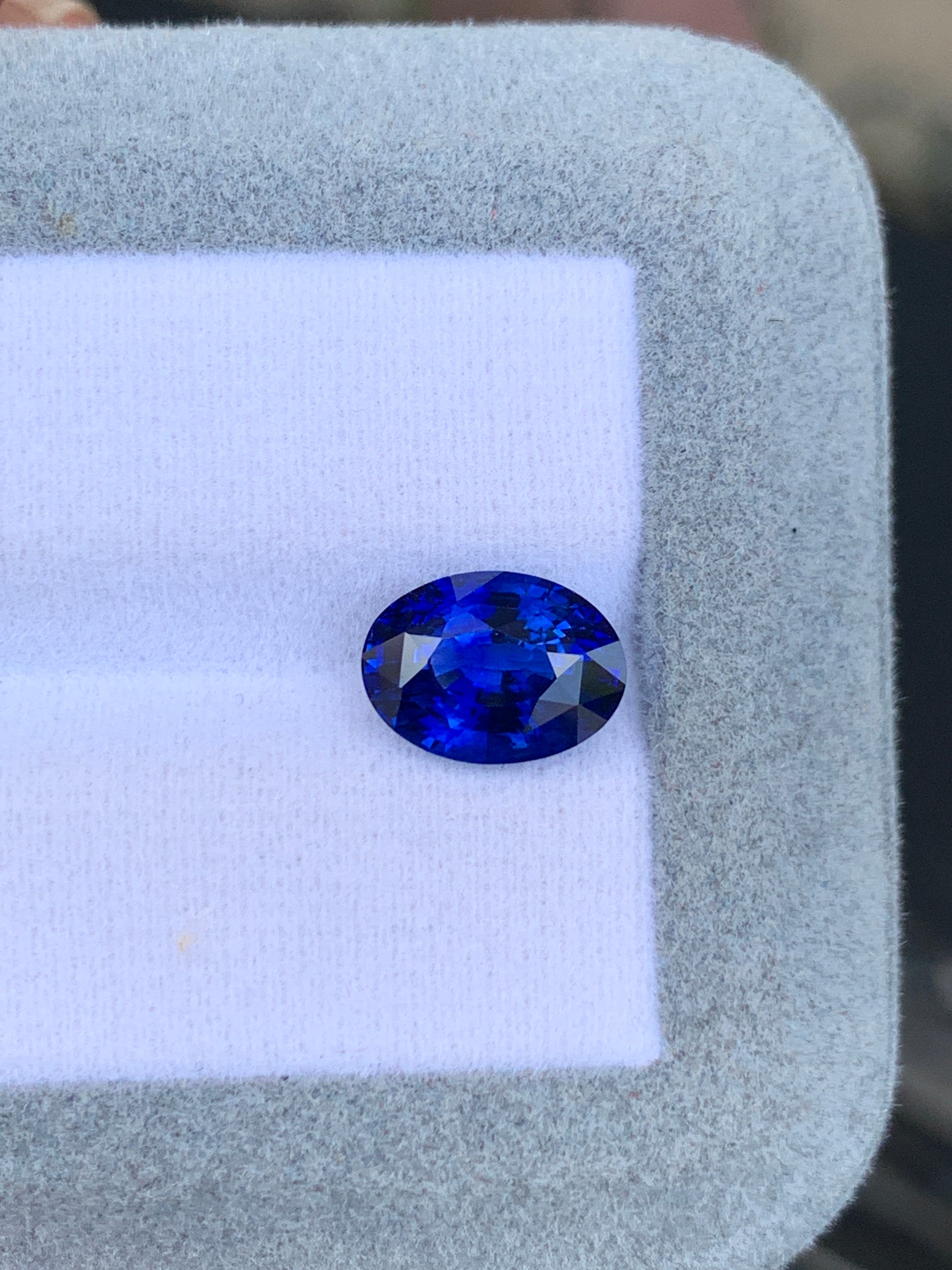 La bague Bonnot Paris « Saphir bleu • 4,02 ct » est ornée d'un saphir taille ovale éclatant, présenté sur un fond blanc dans un écrin gris clair. Cette exquise pierre sri-lankaise arbore une couleur bleu profond et des facettes brillantes qui reflètent magnifiquement la lumière.