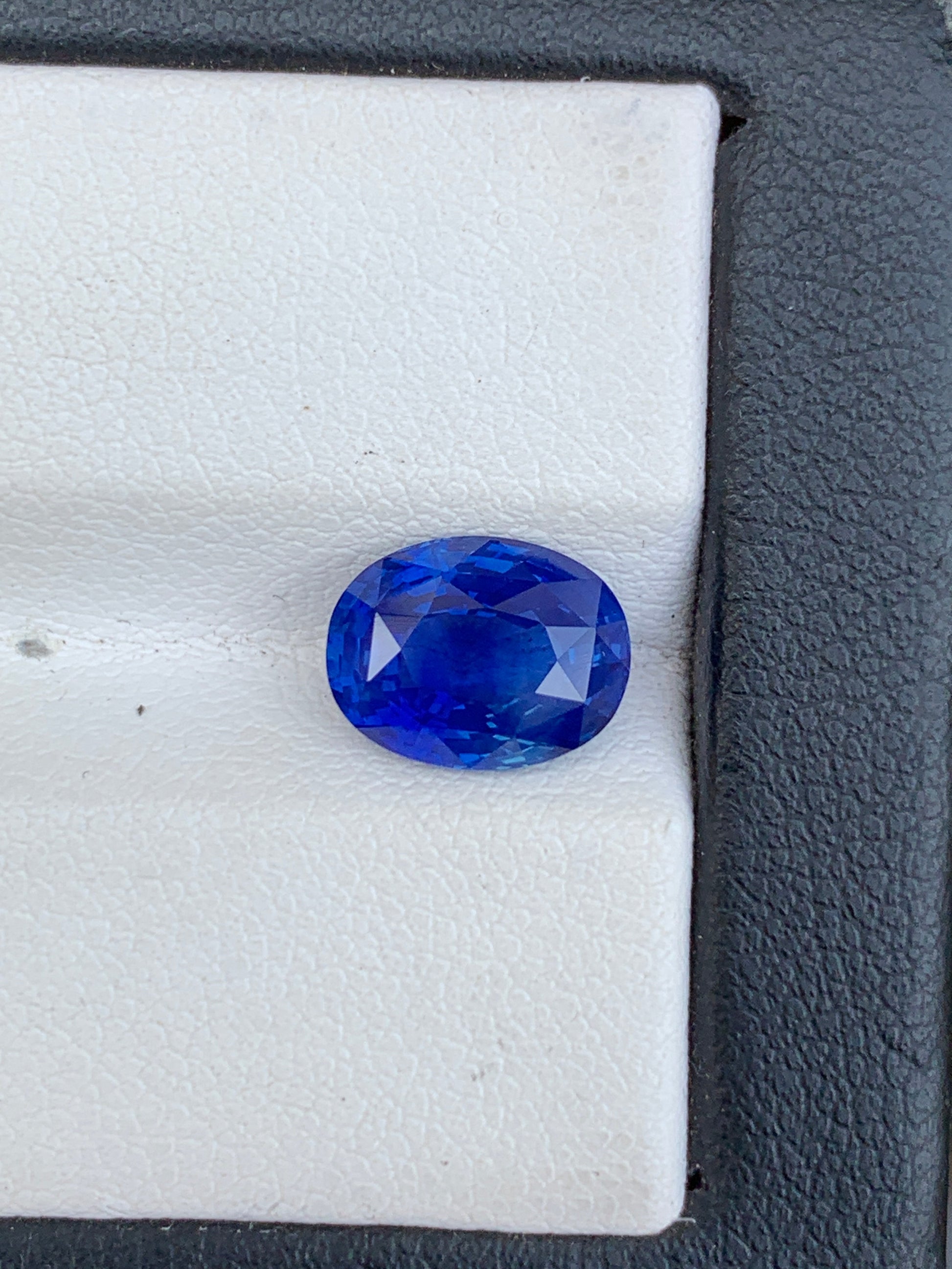 Un Saphir bleu vibrant de 3,59 ct de Bonnot Paris est présenté sur une surface blanche texturée avec une bordure noire, mettant en valeur sa teinte bleu profond et sa clarté grâce à sa taille facettée.