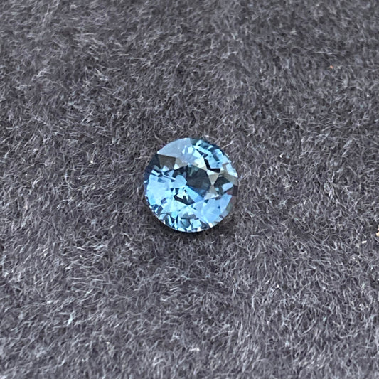 Le Saphir Teal, une pierre précieuse de 1,55 carat de Bonnot Paris, repose élégamment sur un fond texturé sombre, mettant en valeur sa beauté raffinée.