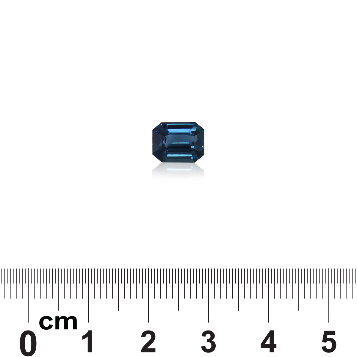 Une petite pierre précieuse Saphir Teal taille émeraude de 2,57 carats de Madagascar par Bonnot Paris est placée sur une surface blanche au-dessus d'une échelle centimétrique allant de 0 à 5, indiquant sa taille.