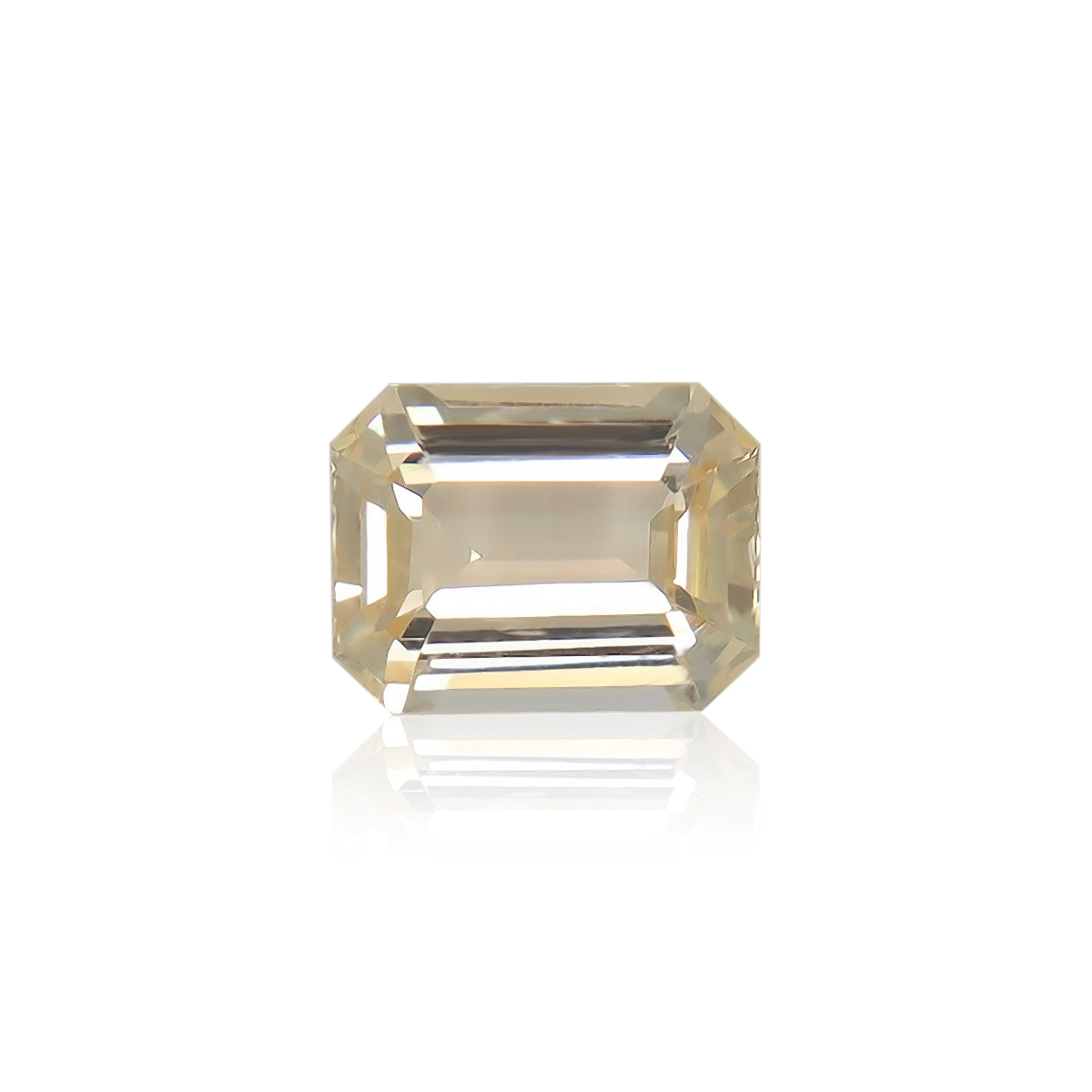 Le Saphir Orange · 1,82 ct de Bonnot Paris est une pierre précieuse taille émeraude éclatante de couleur champagne présentée sur un fond blanc, mettant en valeur ses multiples facettes et sa qualité transparente qui reflètent subtilement la lumière.