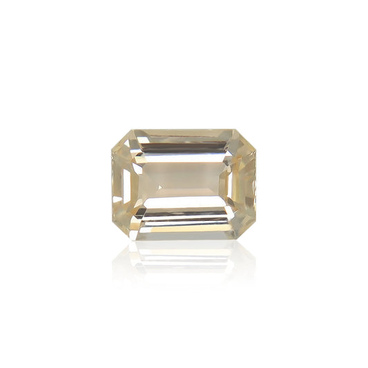 Le Saphir Orange · 1,82 ct de Bonnot Paris est une pierre précieuse taille émeraude éclatante de couleur champagne présentée sur un fond blanc, mettant en valeur ses multiples facettes et sa qualité transparente qui reflètent subtilement la lumière.