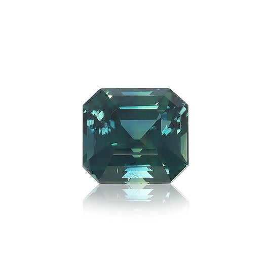 Un diamant taille carrée « Saphir Teal · 3,03 ct » de Bonnot Paris, d'une couleur bleu sarcelle profonde avec des bords biseautés et des facettes réfléchissantes, repose sur une surface blanche projetant une ombre subtile.