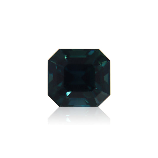 Le Saphir Teal de Bonnot Paris · 3,51 ct, une pierre précieuse rectangulaire bleu profond avec une taille émeraude et des bords biseautés, brille sur un fond blanc uni dans une forme symétrique reflétant une riche teinte bleue.