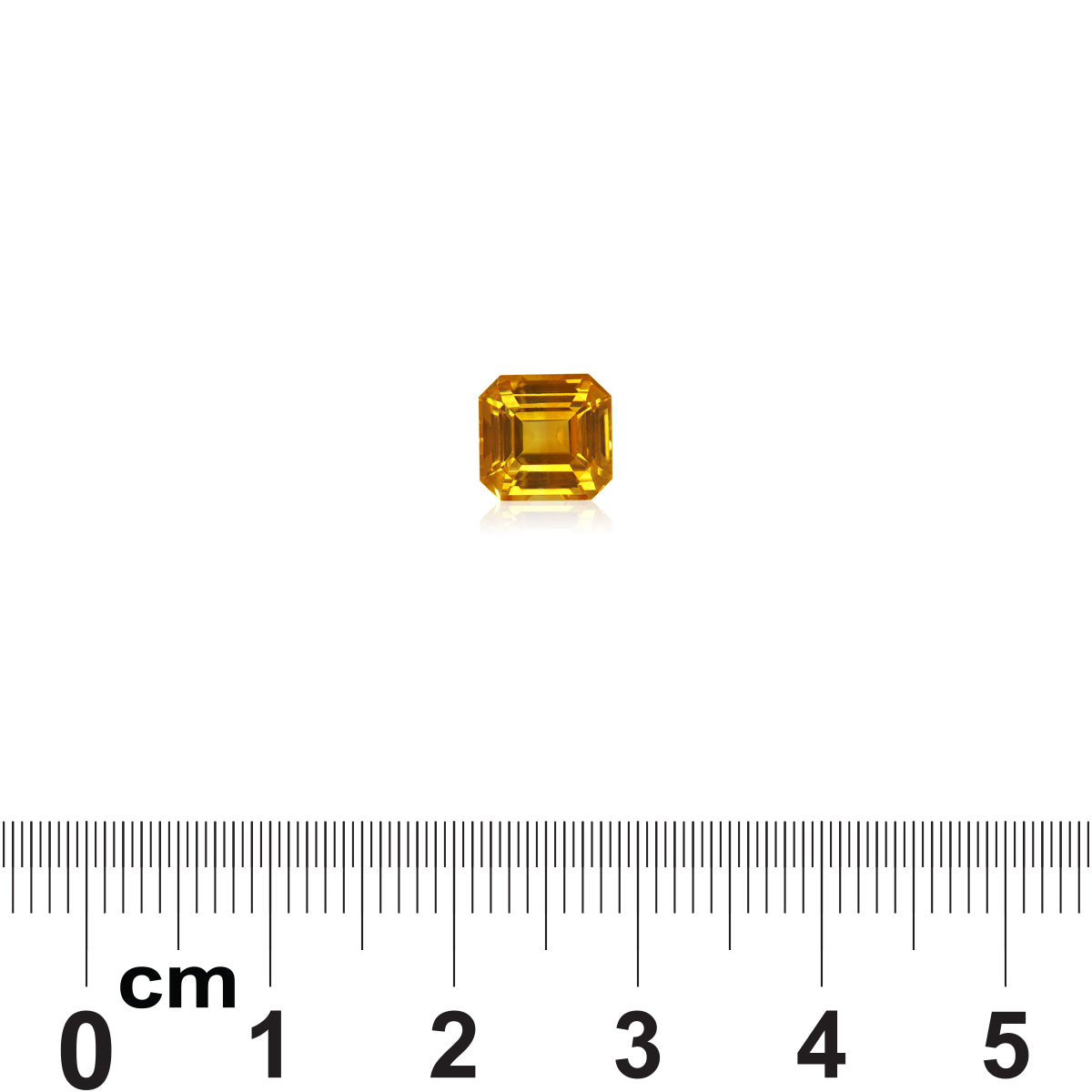 Le Saphir Jaune de 2,04 carats de Bonnot Paris, une pierre précieuse jaune de taille carrée, repose sur un fond blanc, une règle en dessous indiquant sa taille compacte. Il reflète brillamment la lumière, mettant en valeur ses facettes et sa clarté.