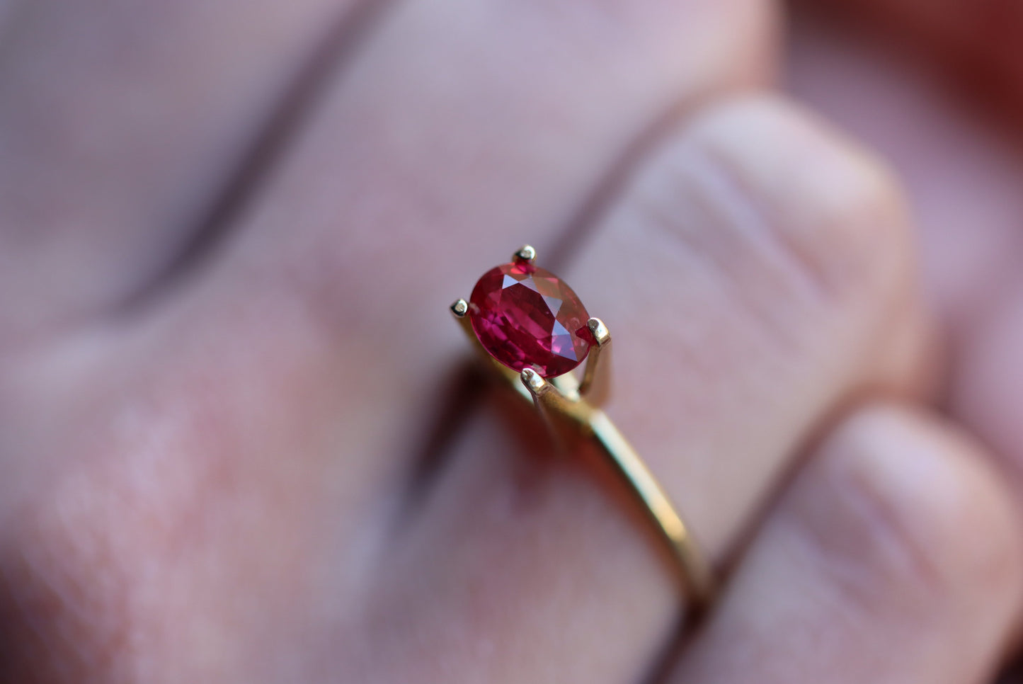 Gros plan d'une main portant la bague en or « Rubis du Mozambique · 1,52 ct » de Bonnot Paris, ornée d'une pierre rouge ovale. L'arrière-plan flou met en valeur la couleur vive et l'éclat de la pierre.