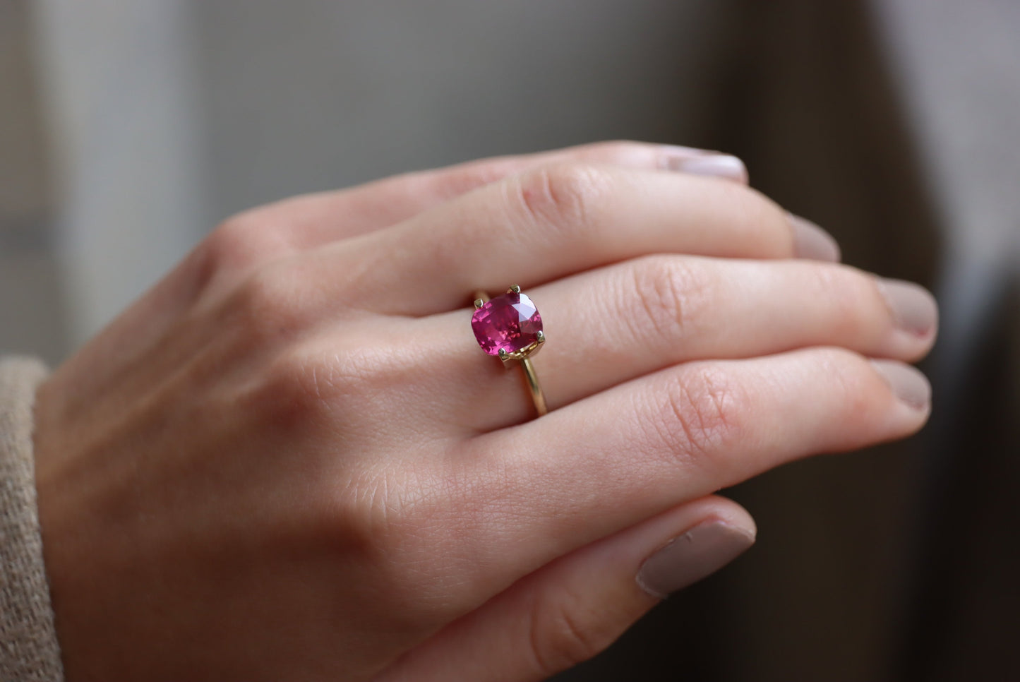Gros plan d'une main ornée du Saphir Rose · 3,02 carats de Bonnot Paris, mettant en valeur une grosse pierre ronde rose vif. La main est ornée d'un vernis à ongles de couleur neutre sur un arrière-plan légèrement flou.