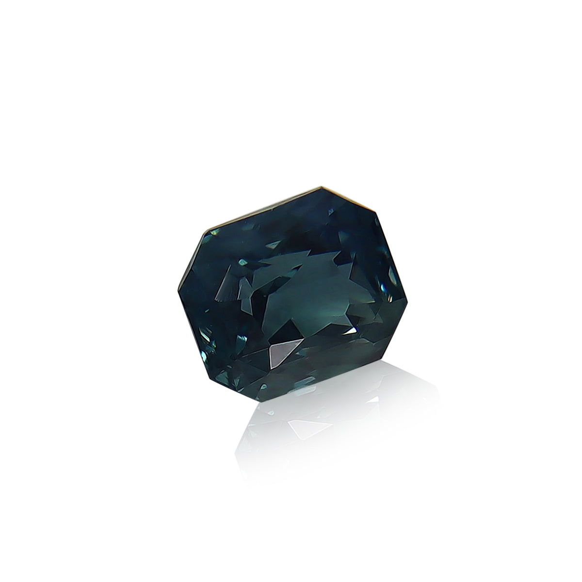 Le Saphir Teal · 1,6 ct de Bonnot Paris, une pierre précieuse bleu-vert profond facettée aux coupes géométriques, est présenté sur un fond blanc uni projetant un reflet élégant.