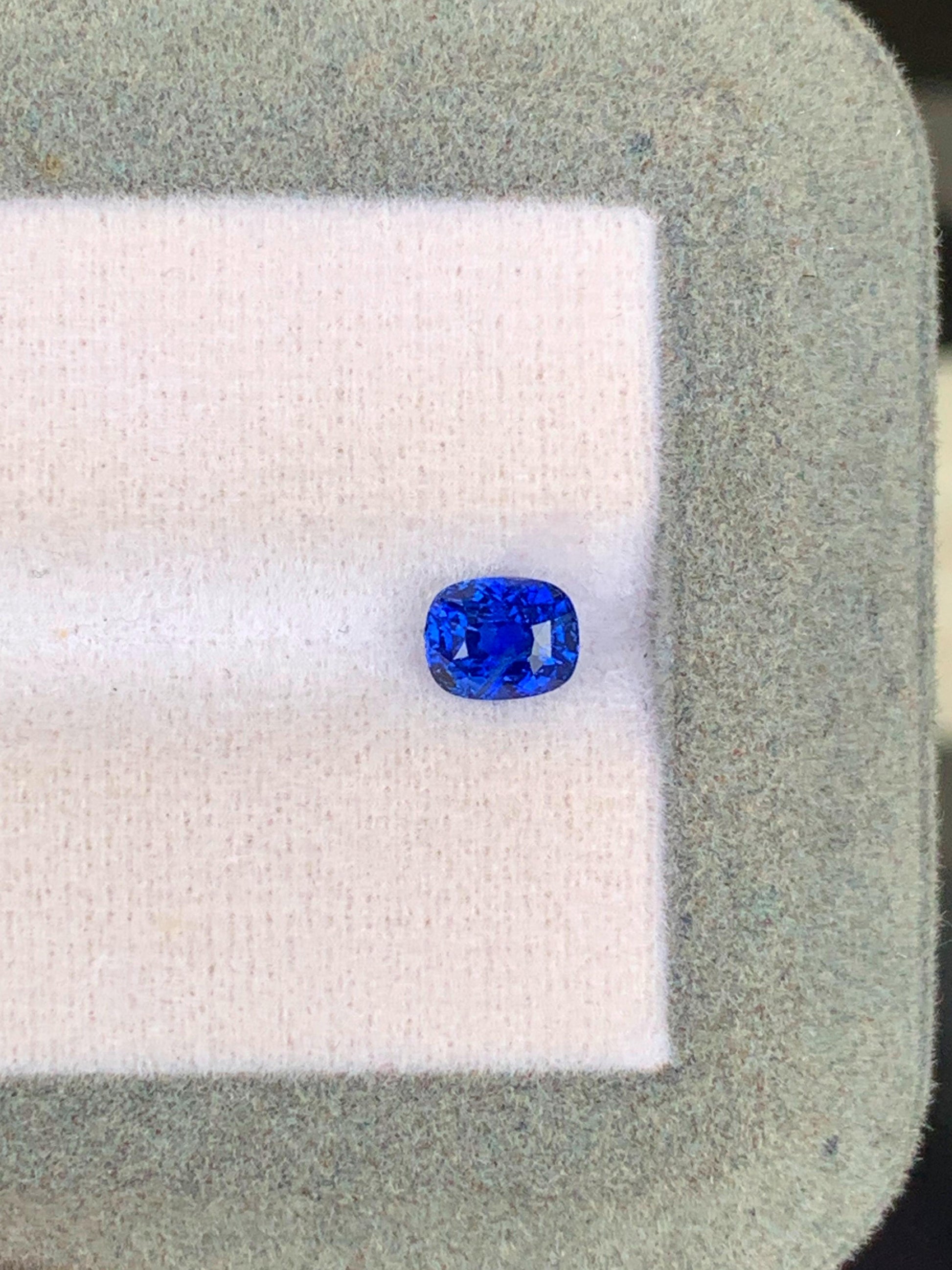 Sur un fond de tissu léger encadré d'une bordure grise texturée, le Saphir Bleu • 1,03ct de [NOUVEAU] Bonnot Paris met en valeur sa taille ovale vive en bleu royal, provenant des célèbres mines du Sri Lanka, incarnant l'essence des véritables pierres précieuses.