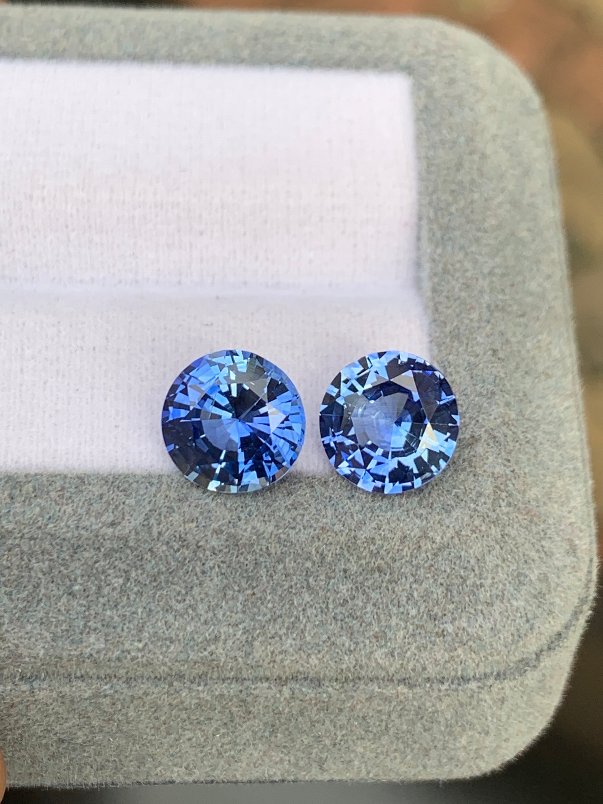 Dans un écrin gris matelassé, deux Saphir bleu de Bonnot Paris, totalisant 5,65 carats, captivent par leur teinte bleue éclatante. Taillées avec soin pour sublimer leur éclat et leur clarté, ces pierres précieuses reposent élégamment sur un fond de tissu blanc.