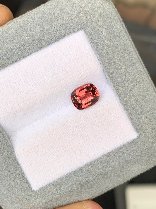 Un Saphir rosé rectangulaire facetté de 1,55 ct de Bonnot Paris est élégamment présenté dans un écrin à bijoux gris avec un intérieur blanc immaculé.