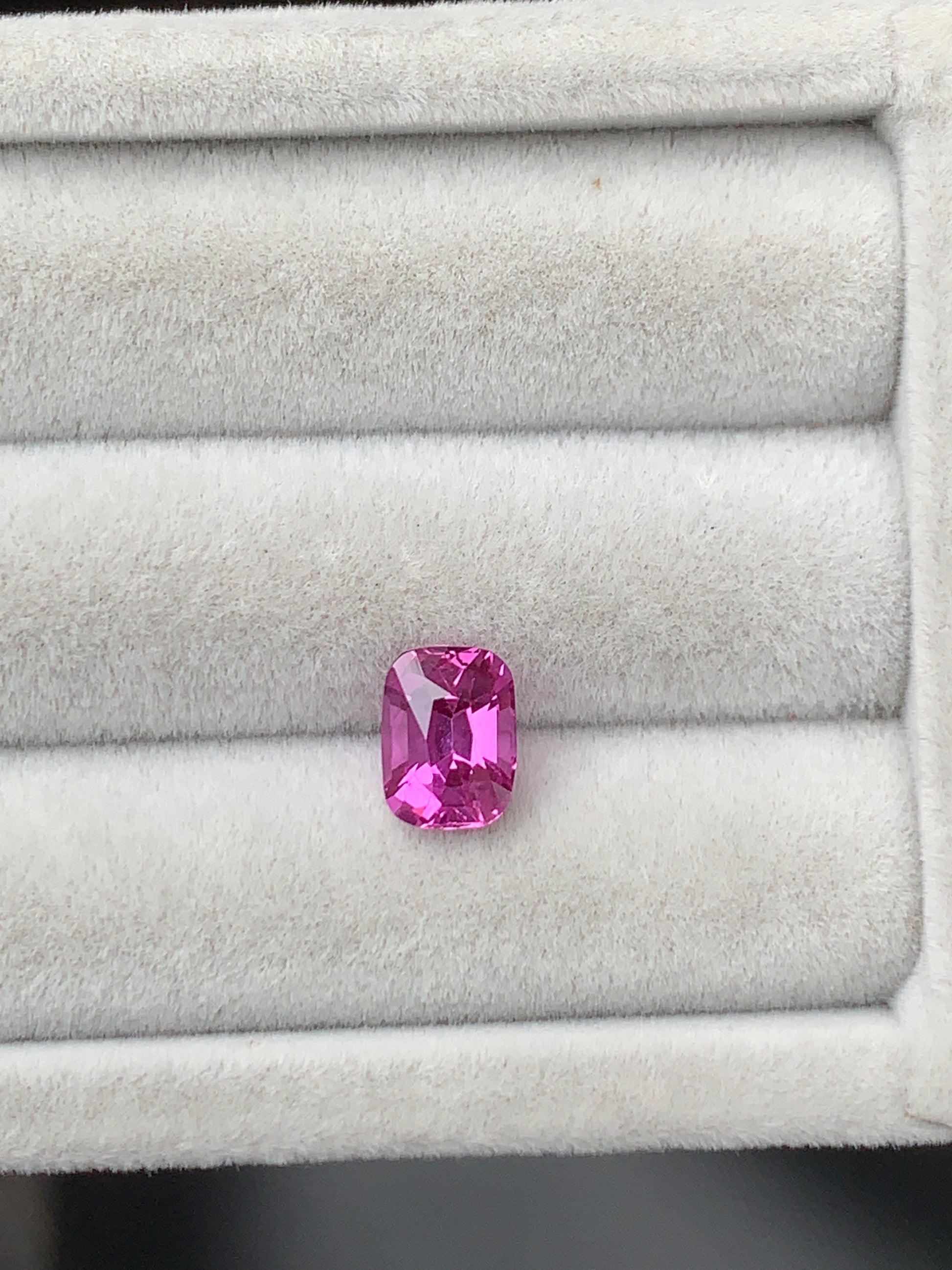 Le Saphir rose Bonnot Paris, une pierre de 2,10 carats aux bords arrondis, est élégamment présenté dans un écrin à bijoux ouvert en velours blanc.