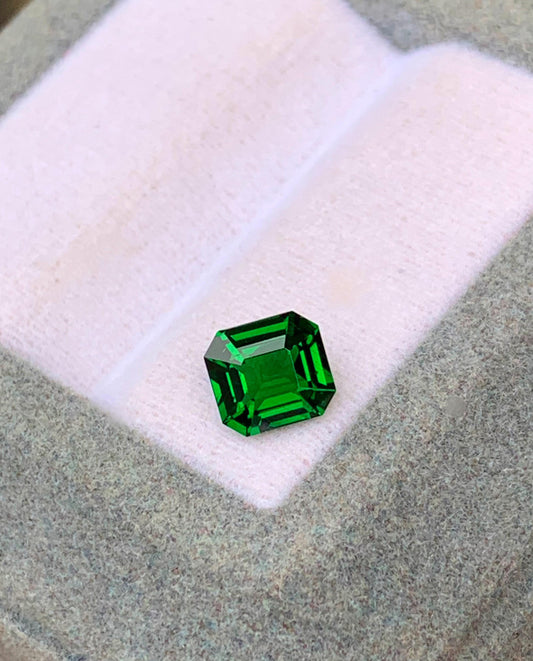 Présentée sur une surface coussinée rose clair dans une boîte grise, la Tsavorite de 1,12 carat de [NOUVEAU] Bonnot Paris capture la lumière avec ses facettes vibrantes, mettant en valeur sa riche teinte et sa clarté.