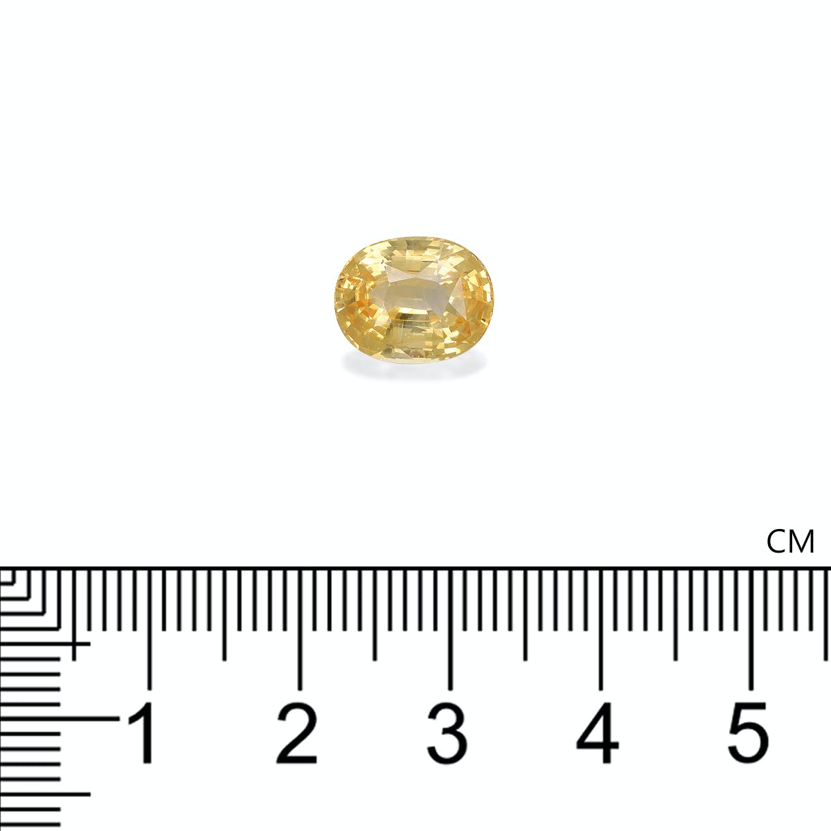 Le Saphir Jaune de 4,5 carats de Bonnot Paris, une pierre précieuse jaune taille ovale, est placé au-dessus d'une règle graduée en centimètres sur un fond blanc uni. La pierre semble mesurer moins d'un centimètre de long.