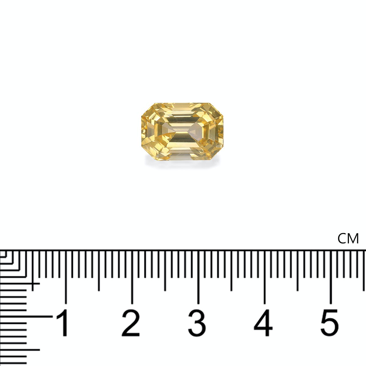 Un Bonnot Paris Saphir Jaune · 7,95 ct, une pierre précieuse taille émeraude de couleur jaune, est positionné au-dessus d'une règle indiquant des mesures de 0 à 6 cm, la gemme mesurant environ 1 cm de large sur un fond blanc uni.